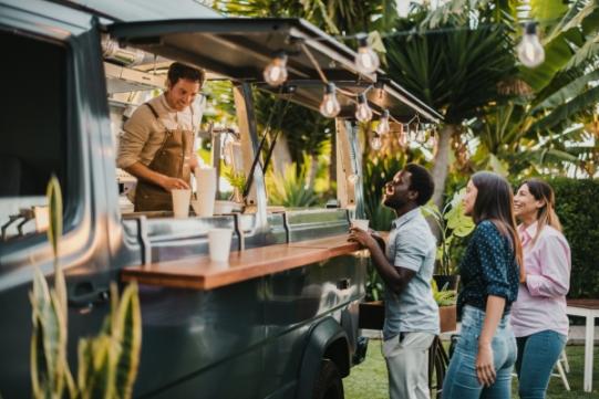 Leute stehen an einem Foodtruck oder Imbisswagen